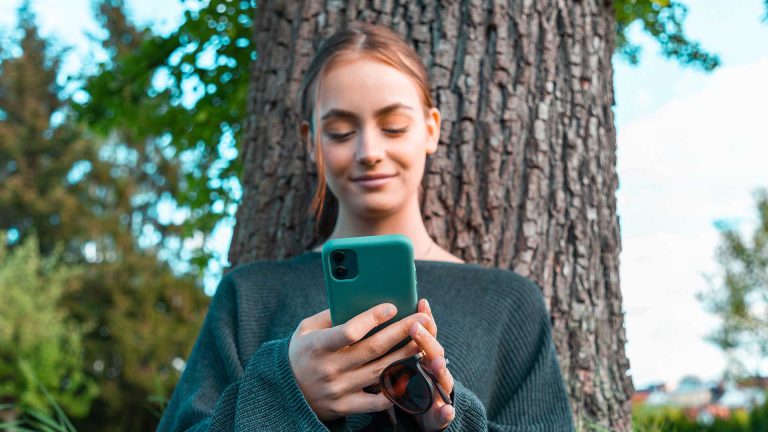 una donna che tiene in mano un telefono e sorride utilizzando un'app