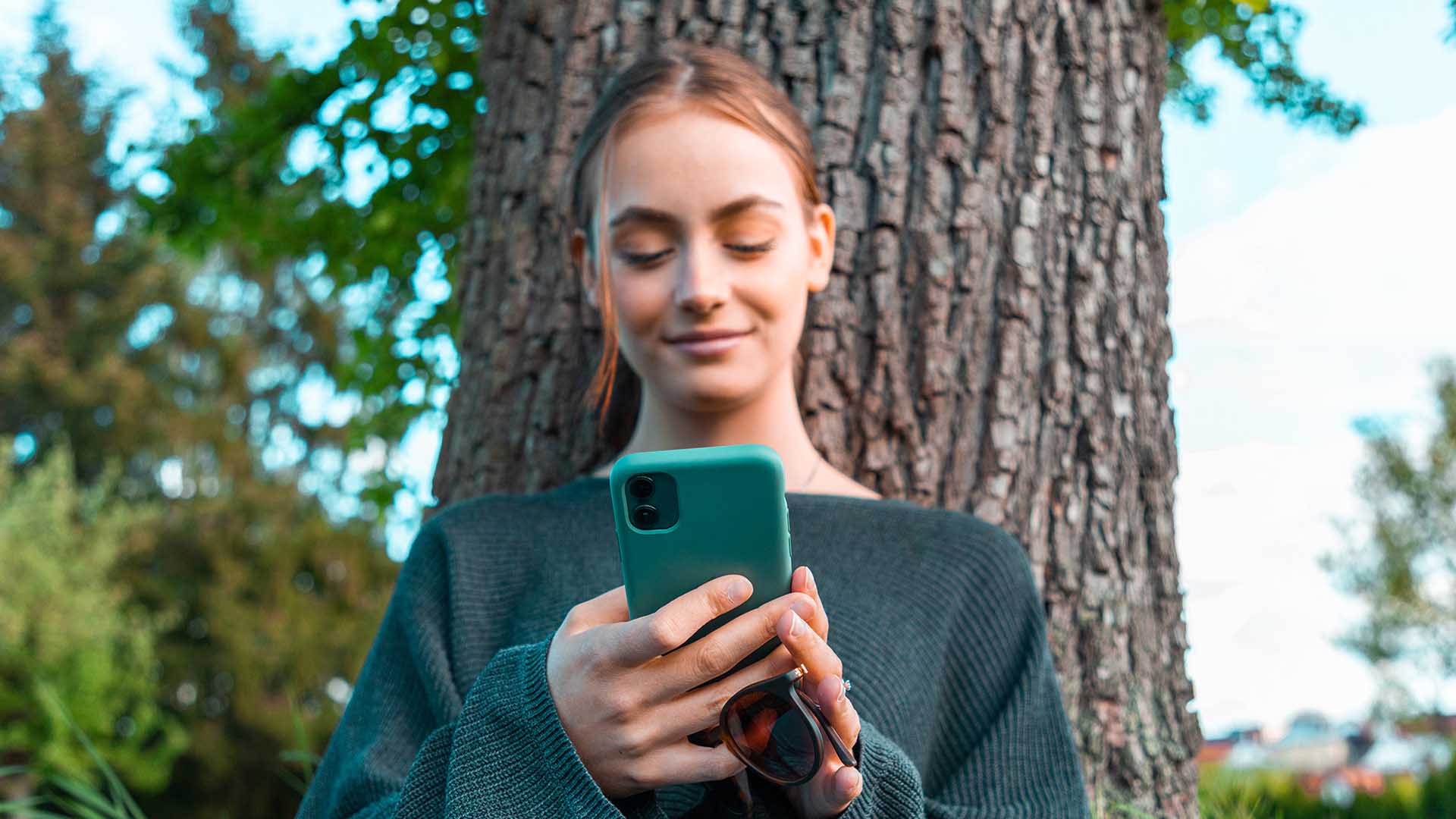 una donna che tiene in mano un telefono e sorride utilizzando un'app